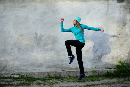 Sporty step woman, gray background, jumping sport outdoor, street, looking away