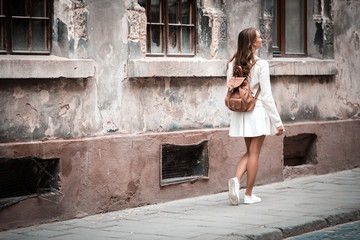 Young woman in casual clothes walking on ancient city, outdoor, textured wall