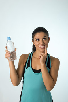 young attractive and beautiful Latin sport woman holding water of bottle thinking if drinking more