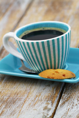 Black coffee in vintage cup with crunchy caramel cookie on wooden surface
