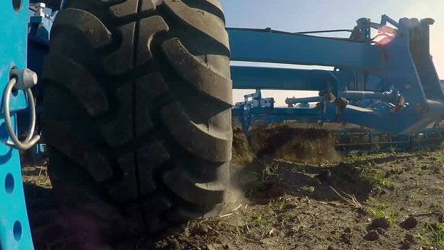 The huge wheel of the cultivator rolls on the ground. Combined cultivator operation