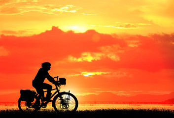 Fototapeta na wymiar Silhouette man and bike relaxing on sunrise background