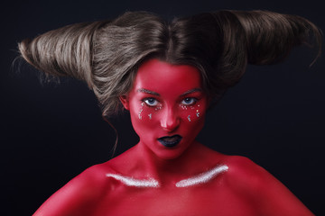 Close up horizontal portrait of a girl in a high fashion, beauty style with red skin, black lips make up at dark background. Devil makeup fashion art design. Halloween holiday concept