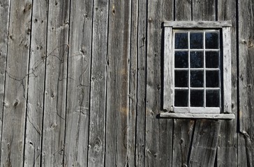 closeup of a window frame on a grey wooden walled building