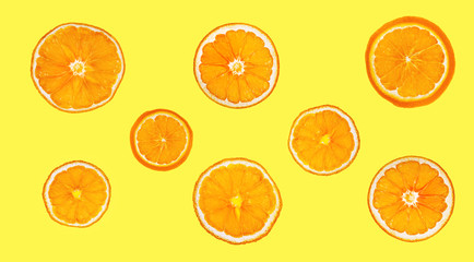 Dry slices of orange isolated on yellow background. A collage of dried orange.