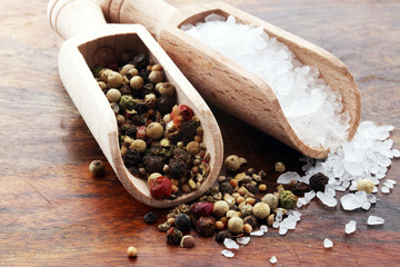 rough salt and mixed peppercorns on wooden shovels.