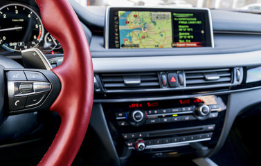 Modern car interior, red steering wheel with media phone control buttons,navigation, screen multimedia system background, car interior details