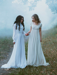 Fototapeta na wymiar Two frightened girls wander in the fog. They are dressed in white vintage dresses. Fairytale Photography