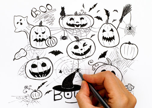 Person hand with black pen drawing Halloween picture.