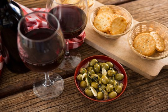 Close-up of marinated olives with glasses of wine