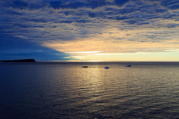 Sunset hidden by dense clouds and reflected in water