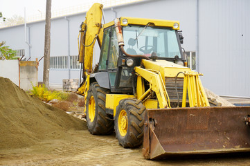 The concept of agronomy, a yellow tractor with a bucket demonstrates work