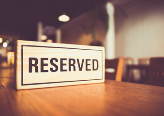 wooden reserved sign with capital letters on dining table in restaurant, retro tone
