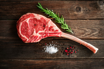 raw Tomahawk steak on wooden background with spices for grilling - Powered by Adobe