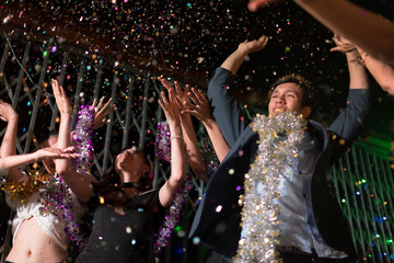 Young people dancing and showered with confetti on a club party on Friday night