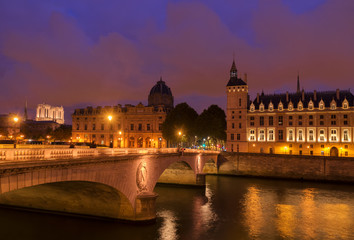 Fototapeta na wymiar Pont au Change bridge and La Conciergerie - ex royal palace and prison at night, Paris, France