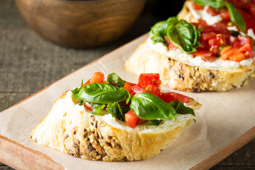 Tomato and cheese fresh made bruschetta. Italian tapas, antipasti with vegetables, herbs and oil on grilled ciabatta and baguette bread.