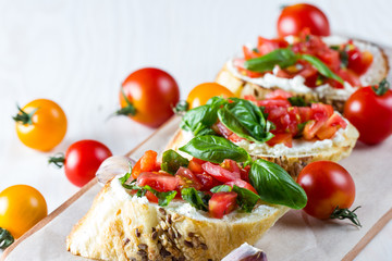 Tomato and cheese fresh made bruschetta. Italian tapas, antipasti with vegetables, herbs and oil on grilled ciabatta and baguette bread.