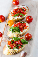 Tomato and cheese fresh made bruschetta. Italian tapas, antipasti with vegetables, herbs and oil on grilled ciabatta and baguette bread.