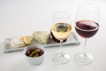 Close-up marinated olives with glasses of wine and cheese in