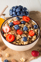 Healthy breakfast concept with oat flakes and fresh berries on rustic background. Food made of granola, muesli. Healthy banana smoothie with blackberries, muslie, strawberries, blueberries and honey.