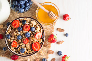 Healthy breakfast concept with oat flakes and fresh berries on rustic background. Food made of granola, muesli. Healthy banana smoothie with blackberries, muslie, strawberries, blueberries and honey.