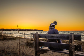 Women sitting on bench on beach with sunset