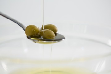 Green olive oil being poured in spoon