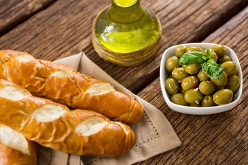 Marinated olives with olive oil and breakfast on wooden table