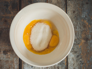 raw eggs with sugar in a deep white beaker for whipping