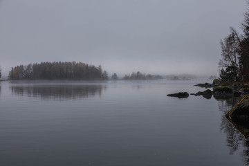 Obraz na płótnie Canvas Late fall in Finland. Dark cold foggy morning in the lake