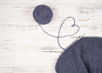 a ball of wool with knitting needles and knitted fabric.
thread in the shape of a heart on a...