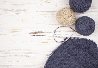  ball of wool with knitting needles and knitting on wooden white background