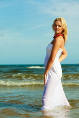 Fototapeta na wymiar Blonde woman wearing dress walking in water