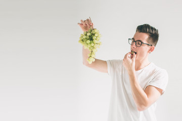man holding grape, close up. concept. isolated on white. Nerd is wearing glasses.