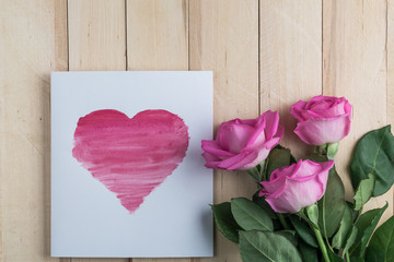 three roses on wooden background with heart