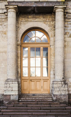 Fototapeta na wymiar Background of city buildings from limestone. Vintage arched door. The old town of Gatchina. Russia.