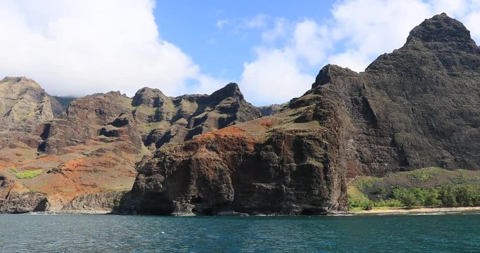 Boat cruise along remote Na Pali cliff coast Kauai Hawaii. Na Pali coast with mountain cliff steep into water. Oldest Hawaiian Island. Garden Isle. Economy is tourism based. Water and tropical beach.