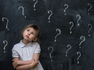 Little girl with question mark on blackboard. Concept for confusion, brainstorming and choice.