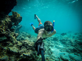 Naklejka na ściany i meble Underwater wide angle selfie of muscular swimmer in a crystal water