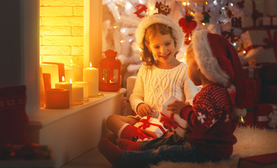 happy children with christmas presents near Christmas tree and fireplace
