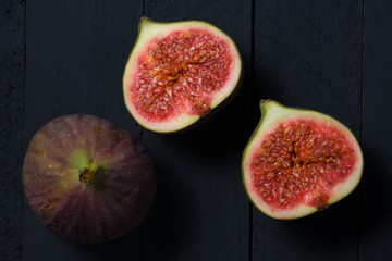 One whole and sliced figs on the wooden table.