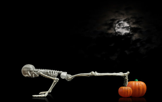 Halloween skeleton doing pushups on a pumpkin under a nice night time moon covered with dark clouds.
