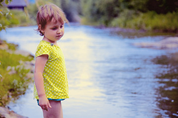 Little girl having fun by river at summer (Holiday, rest, happy childhood, games, nature concept)
