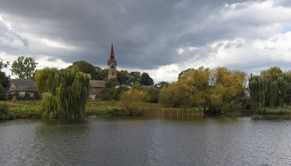 Panorama of catholic church on lake shore  in the village in autumn