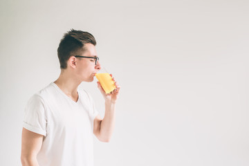 Happy man holding glass of orange juice isolated on white background. Nerd is wearing glasses.