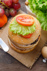 Hamburger with grilled pork and fresh vegetable on wooden table