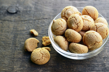 Amaretti cookies in a  glass bowl on old wooden background.Italian amarettini biscuits.Amarettini cookies.Tasty Italian amaretti biscuits.Selective focus.