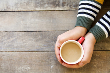Woman hands holding hot coffee on wooden table