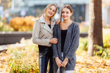 Fototapeta premium Two girls sit on the bench and lauch to camera